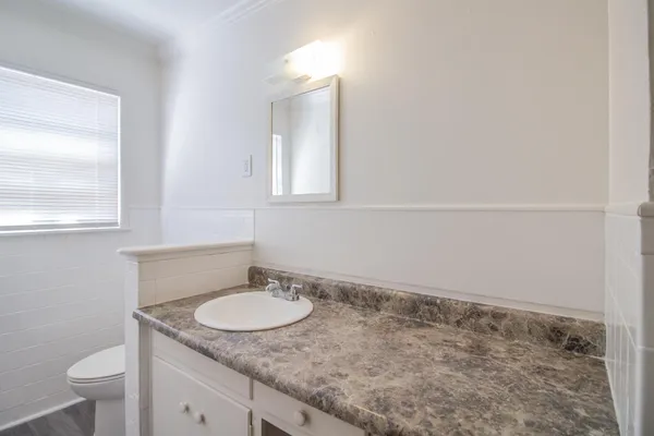 a bathroom with a granite countertop sink and a toilet