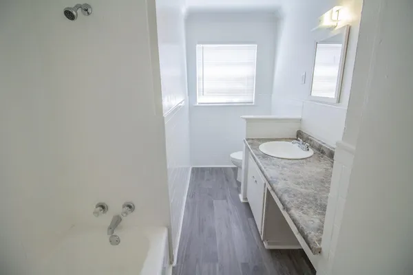 a bathroom with a granite countertop sink a toilet and a bathtub