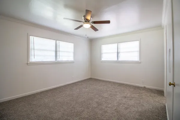 an empty room with windows and fan