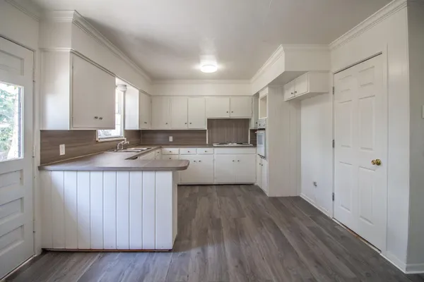 a kitchen with kitchen island granite countertop a sink cabinets and wooden floor