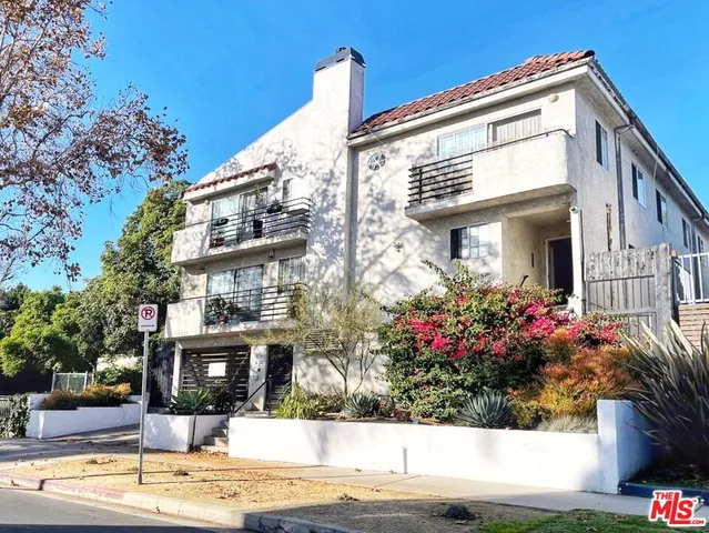 a view of a white building among the street and flowers