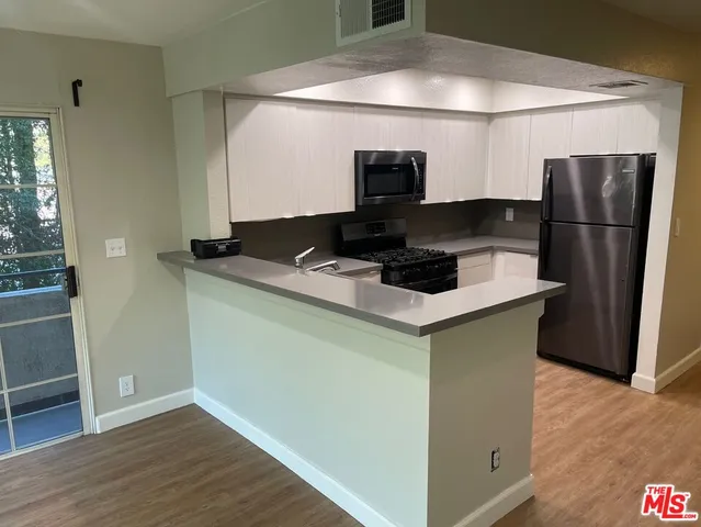 a kitchen with stainless steel appliances a microwave a refrigerator and a sink