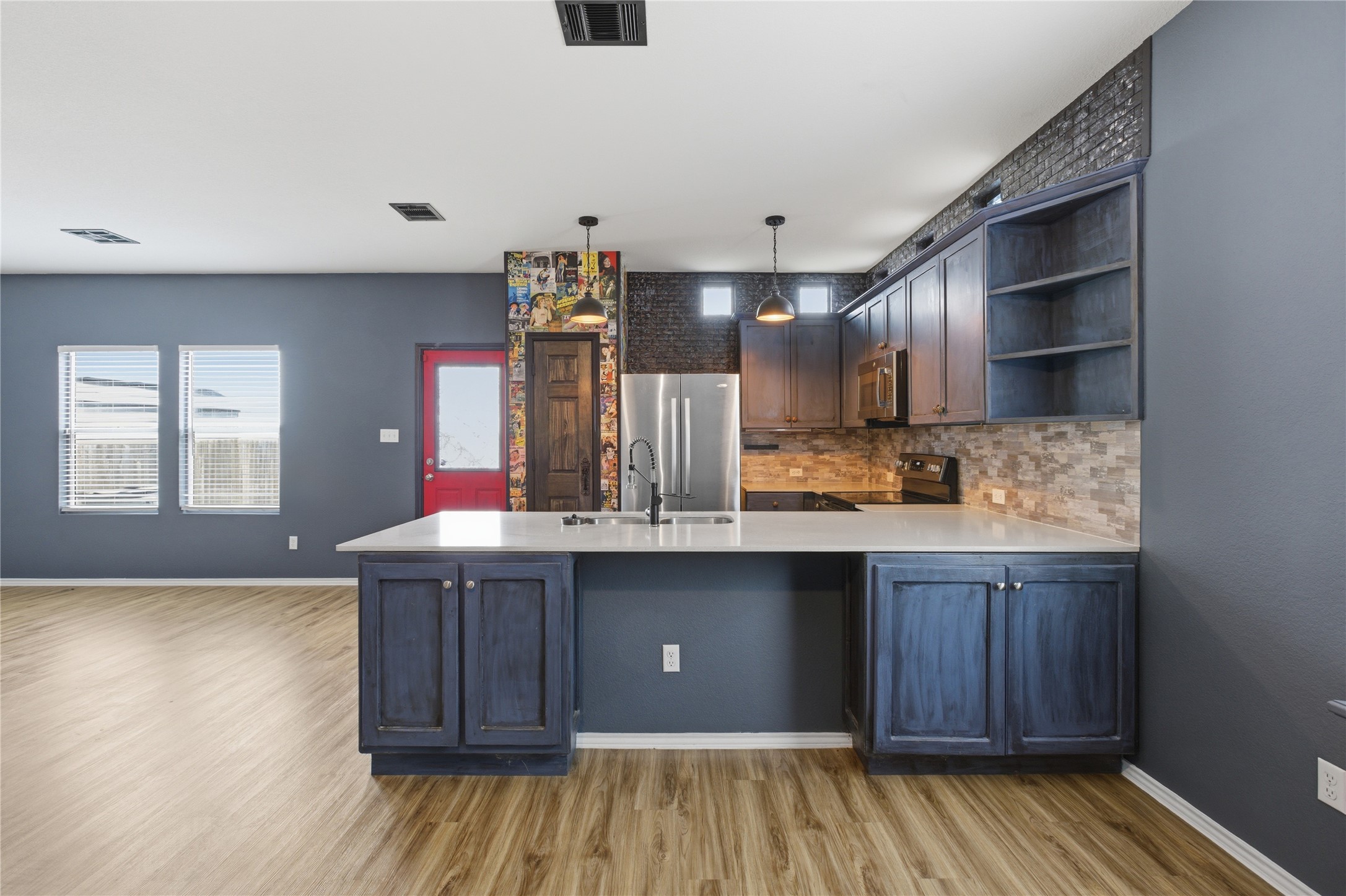 116 Night Riders Way Jarrell, TX 76537 - Photo 16 of 40 Open-concept kitchen featuring an island with white countertop, dark blue cabinetry, mosaic tile backsplash, and stainless steel appliances
