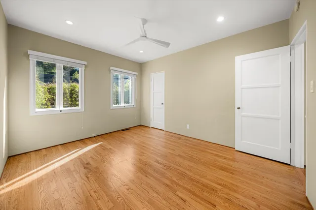 an empty room with wooden floor and windows