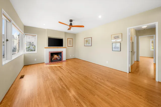a big room with wooden floor a fireplace and a window