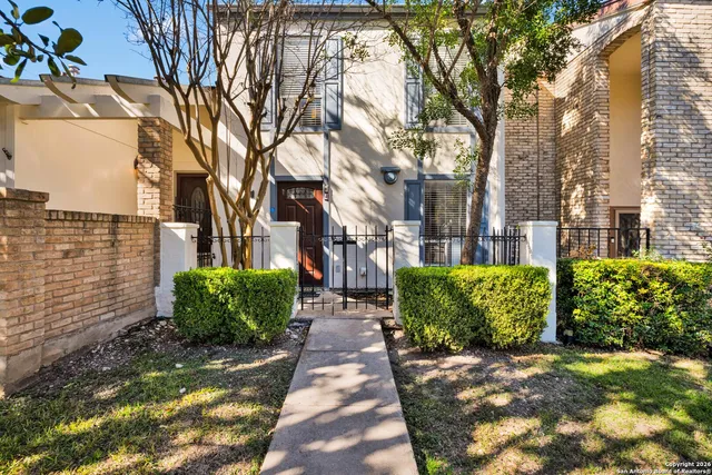 a view of a brick house with a large windows plants and large trees