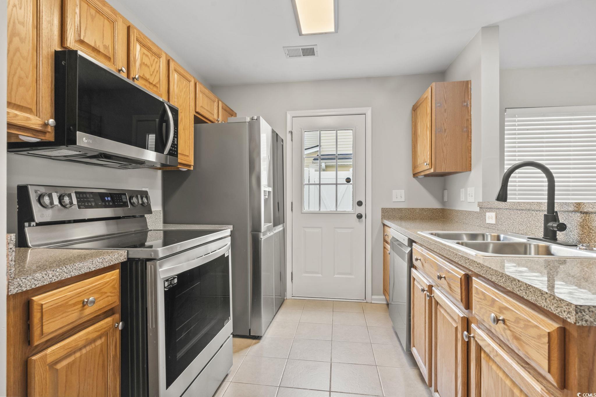 103 Barnacle Lane, Unit R5 Little River, SC 29566 - Photo 12 of 33 Kitchen featuring appliances with stainless steel finishes, light tile patterned flooring, light countertops, and brown cabinetry