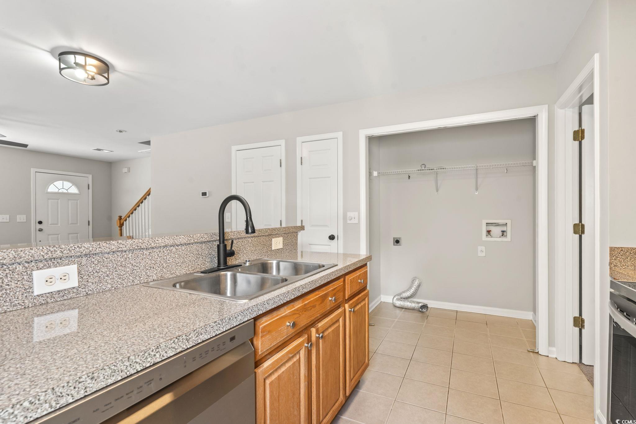 103 Barnacle Lane, Unit R5 Little River, SC 29566 - Photo 9 of 33 Kitchen with light countertops, light tile patterned floors, stainless steel dishwasher, and brown cabinetry