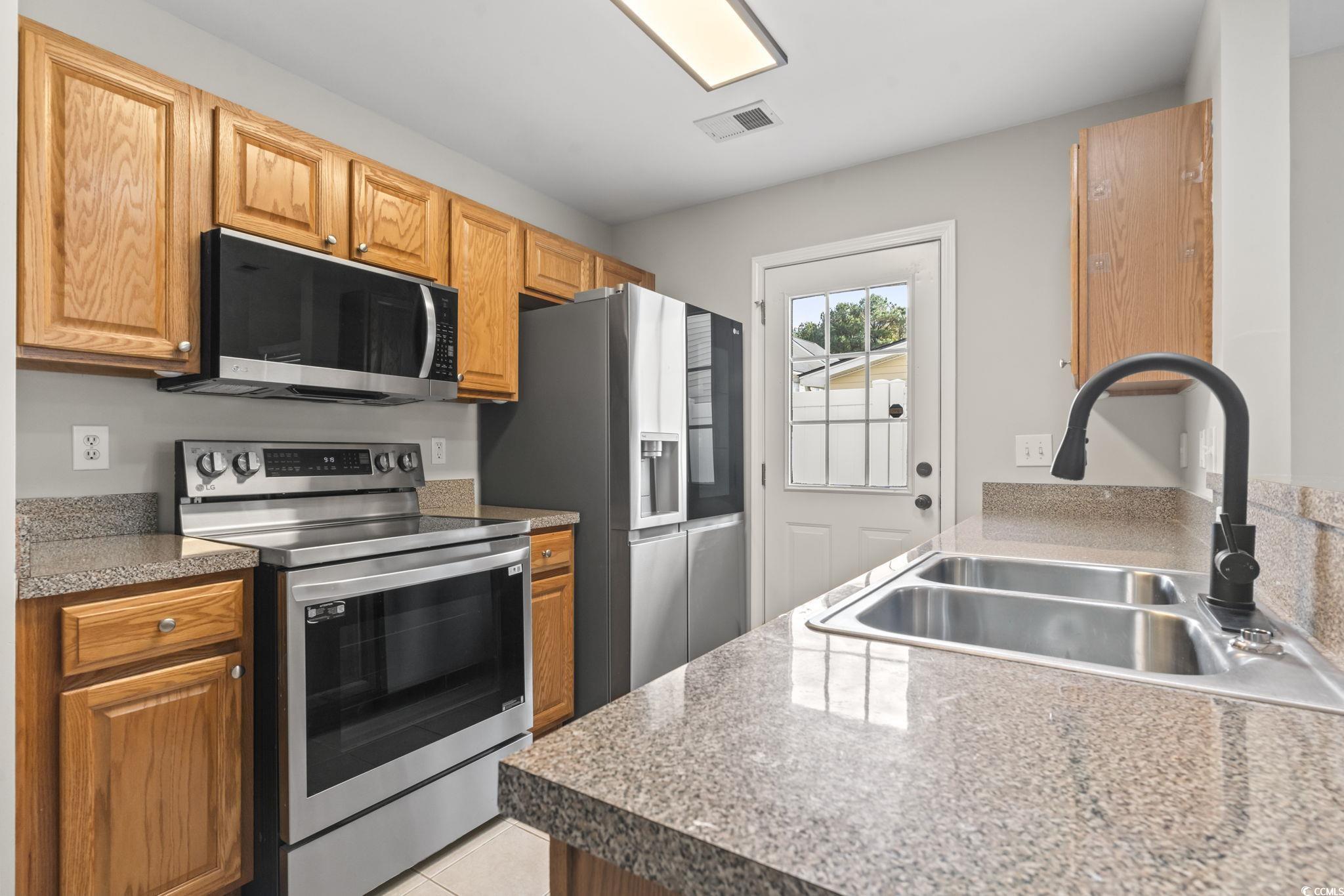 103 Barnacle Lane, Unit R5 Little River, SC 29566 - Photo 10 of 33 Kitchen with appliances with stainless steel finishes, light tile patterned floors, and brown cabinetry