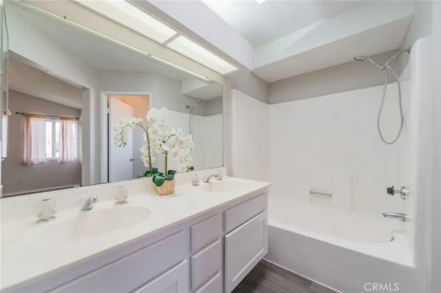 a bathroom with a double vanity sink bathtub and shower