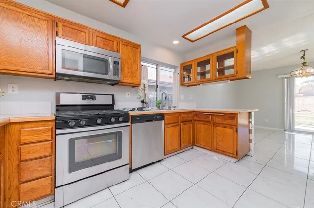 a kitchen with stainless steel appliances granite countertop a stove top oven a sink dishwasher and white cabinets with wooden floor