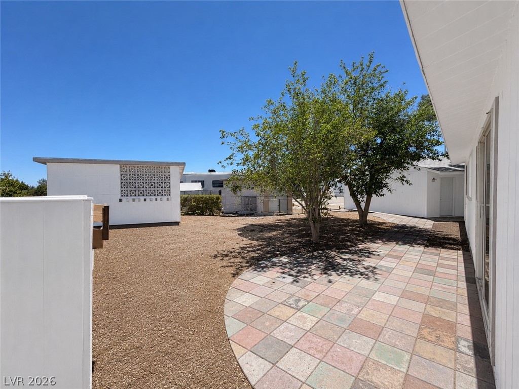 1611 West Blosser Ranch Road Pahrump, NV 89060 - Photo 14 of 25 A private yard with mature trees and a colorful paver patio offers an inviting outdoor retreat.