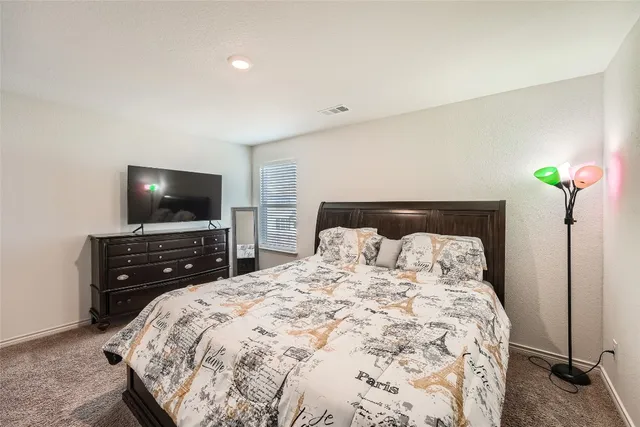 a bedroom with a bed and a flat tv screen on dresser