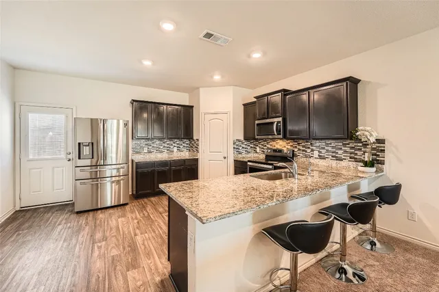 a kitchen with stainless steel appliances kitchen island granite countertop a refrigerator and a stove top oven