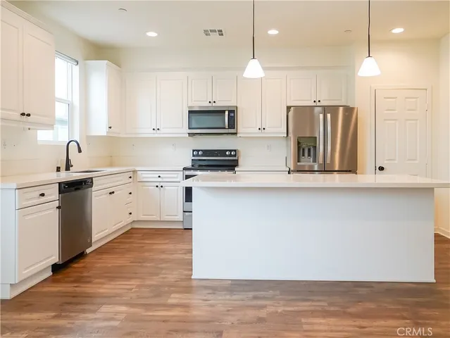 a kitchen with stainless steel appliances kitchen island granite countertop a stove a sink and a refrigerator