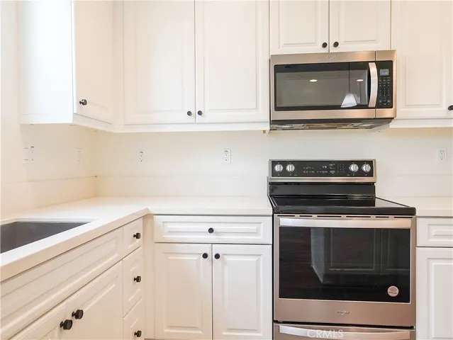a kitchen with stainless steel appliances granite countertop white cabinets and a stove top oven