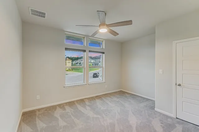 an empty room with windows and fan