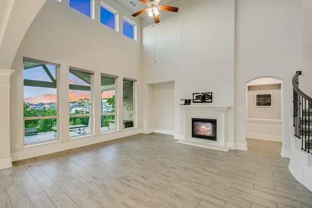 a view of an empty room with wooden floor fireplace and a window