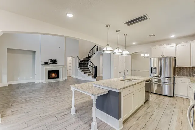 a large kitchen with stainless steel appliances kitchen island a large counter top a sink refrigerator and cabinets