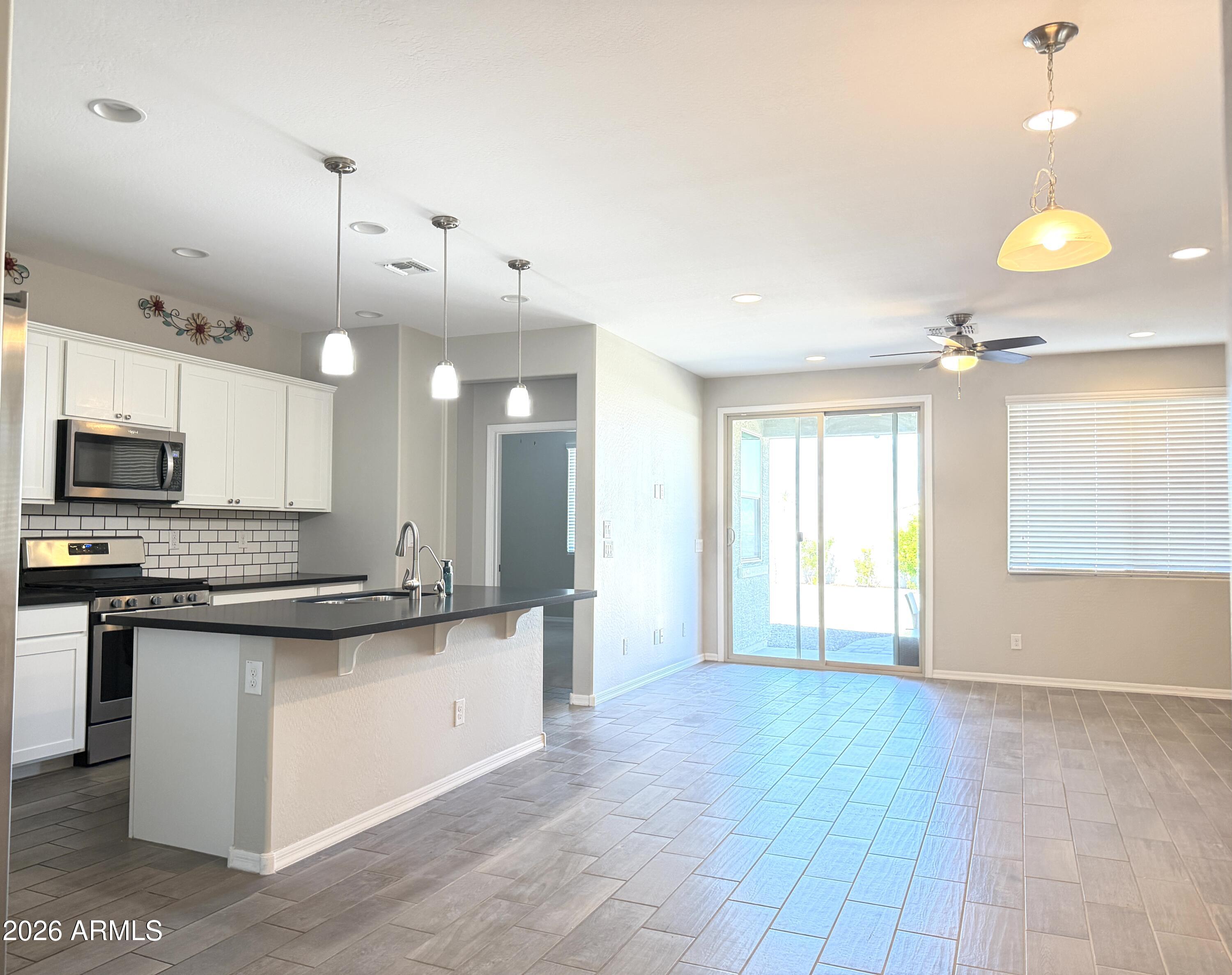 2314 East Harwell Road Phoenix, AZ 85042 - Photo 6 of 32 a large kitchen with kitchen island a stove a sink a center island and wooden floor