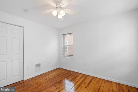 an empty room with wooden floor fan and windows