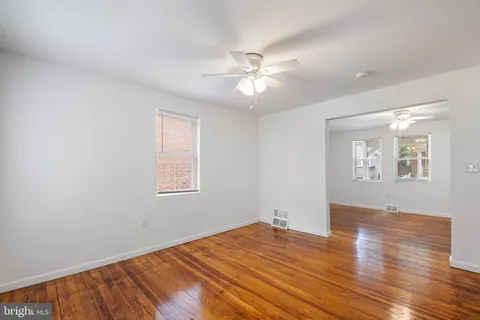 a view of empty room with wooden floor and fan
