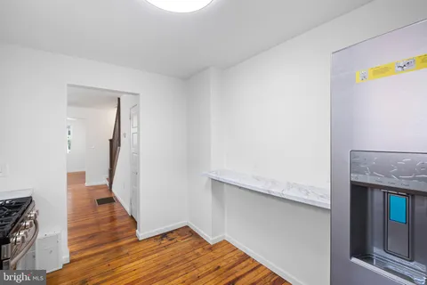 a view of an empty room with wooden floor and a fireplace
