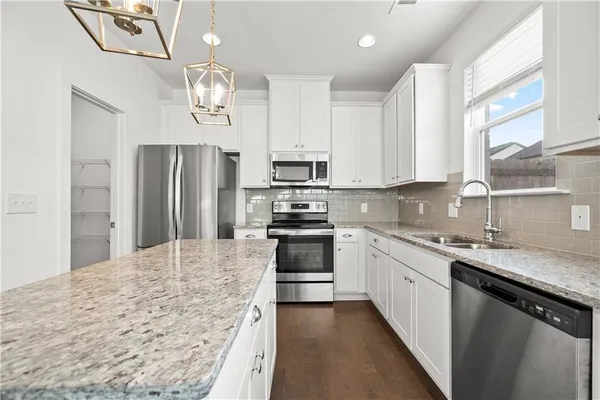 a kitchen with stainless steel appliances granite countertop a stove refrigerator sink and microwave