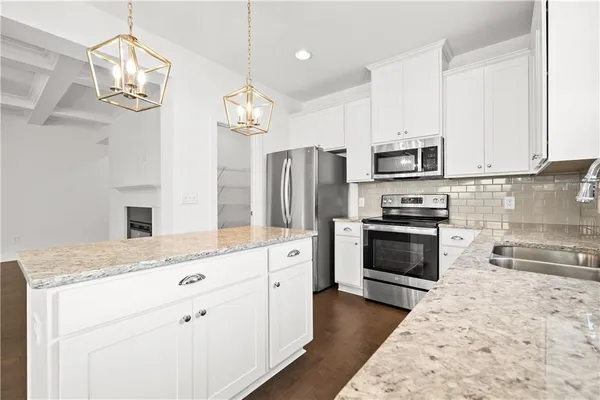 a kitchen with kitchen island granite countertop stainless steel appliances a stove oven a sink cabinets and a counter top space