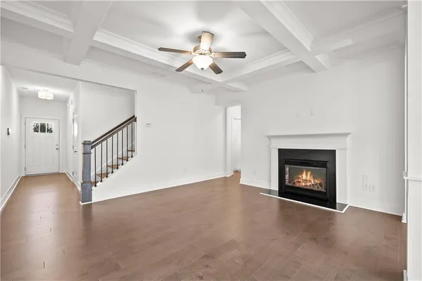a view of an empty room with wooden floor fireplace and a window