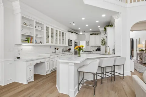 a kitchen with stainless steel appliances kitchen island granite countertop a table chairs sink and cabinets