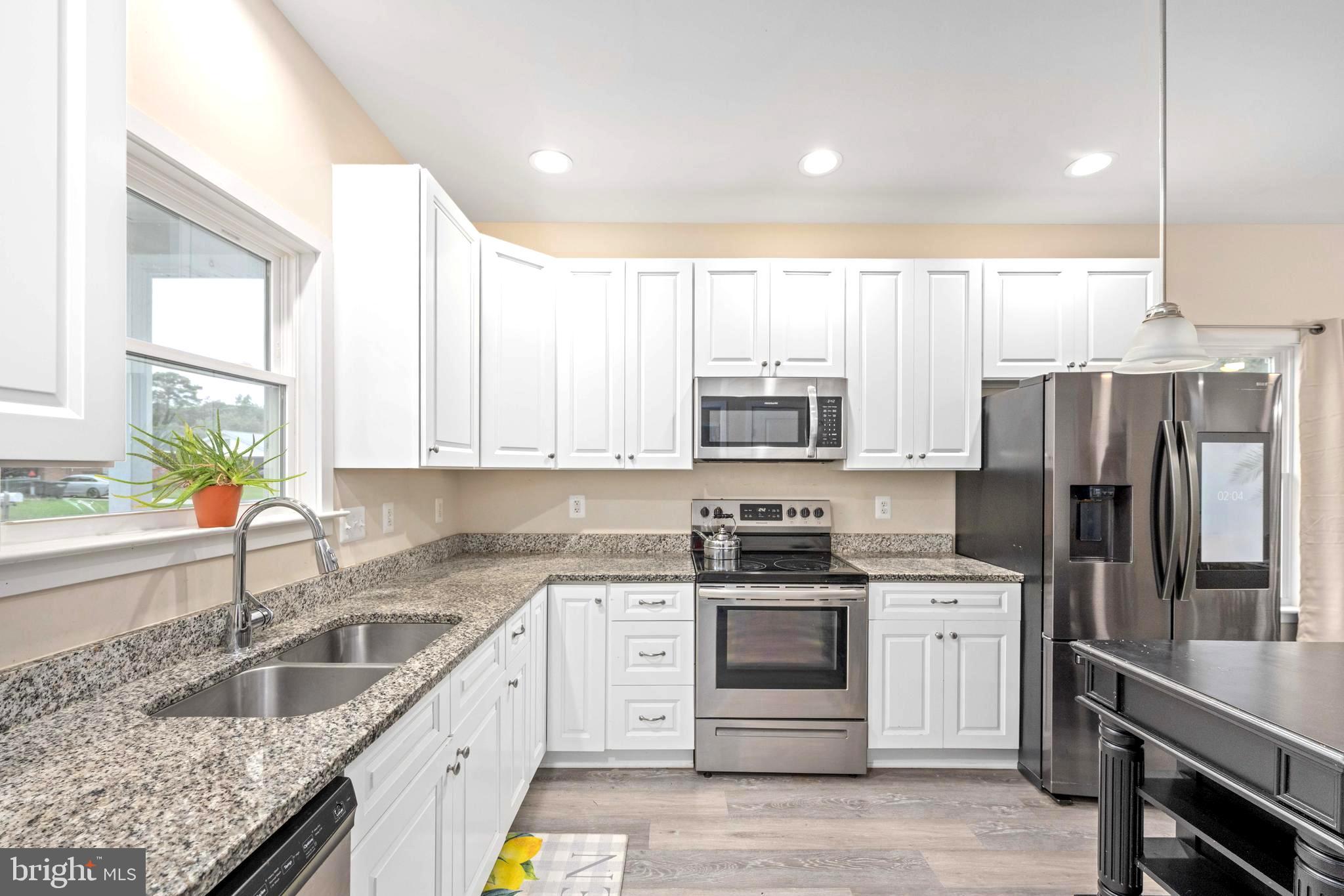 137 12th Street Colonial Beach, VA 22443 - Photo 22 of 66 a kitchen with stainless steel appliances granite countertop white cabinets a sink a stove a refrigerator and white cabinets