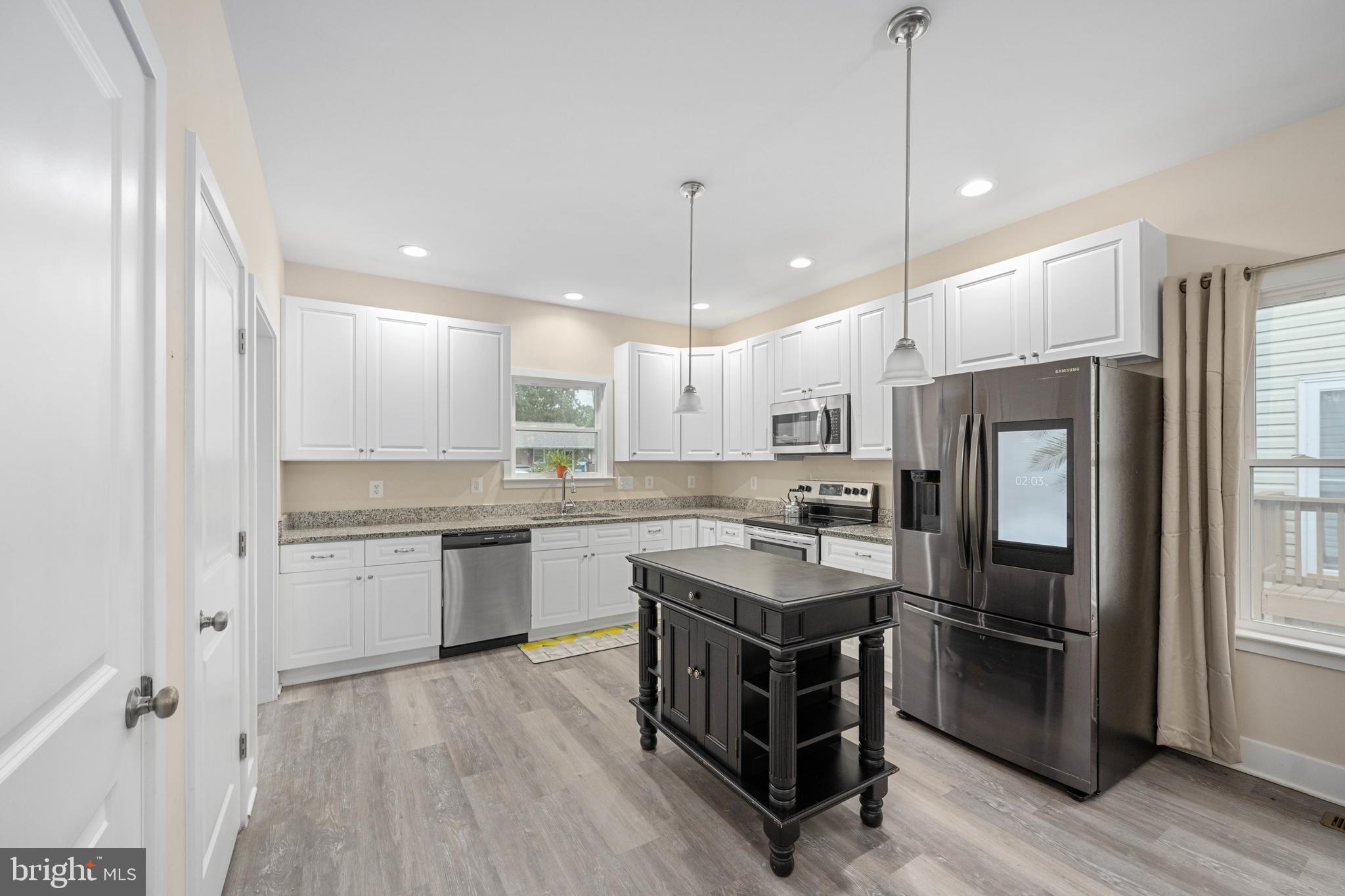 137 12th Street Colonial Beach, VA 22443 - Photo 26 of 66 a kitchen with a white center island a sink stainless steel appliances and cabinets