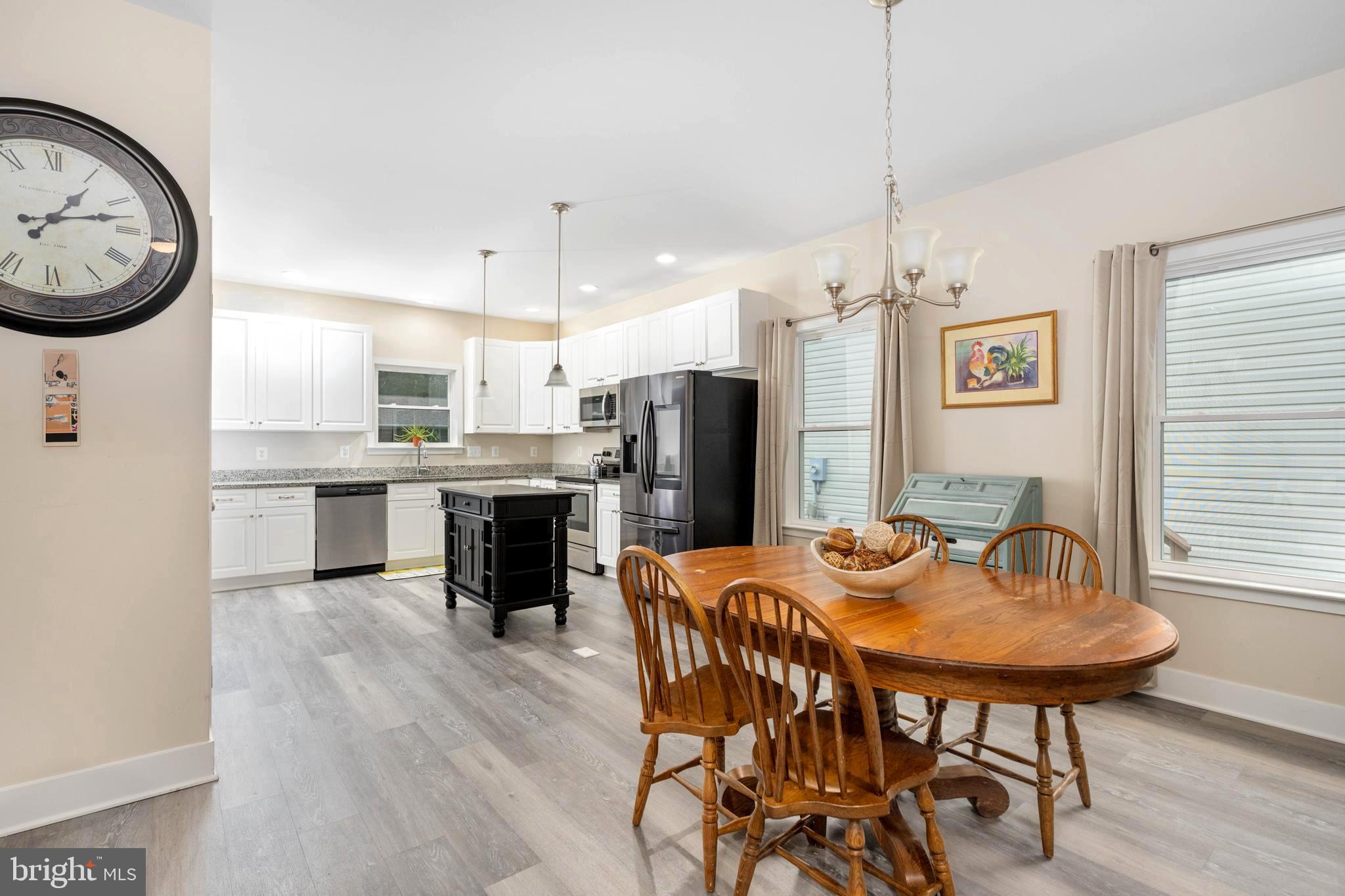 137 12th Street Colonial Beach, VA 22443 - Photo 28 of 66 a kitchen with stainless steel appliances kitchen island granite countertop a dining table chairs and white cabinets