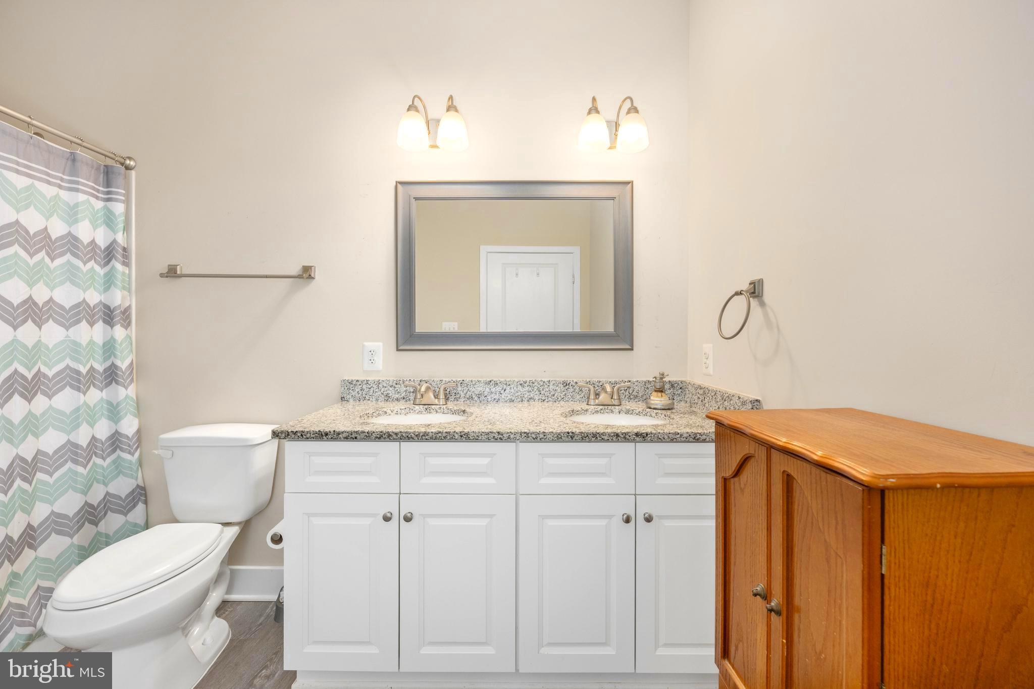 137 12th Street Colonial Beach, VA 22443 - Photo 46 of 66 a bathroom with a granite countertop toilet sink and mirror
