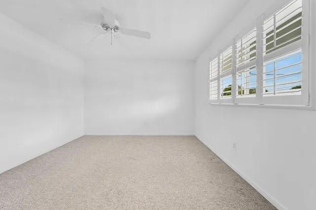 an empty room with a window and a ceiling fan