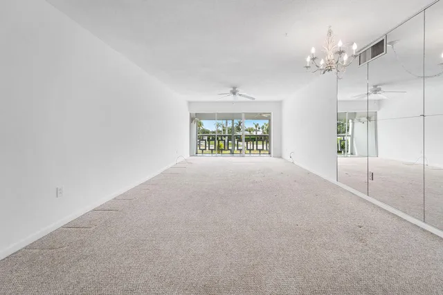 en empty room with windows and chandelier fan