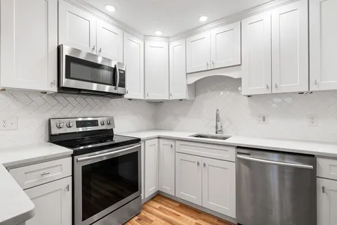 a kitchen with white cabinets and stainless steel appliances