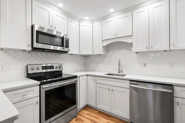 a kitchen with white cabinets and stainless steel appliances
