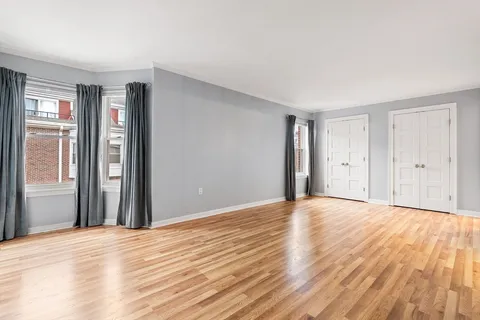 a view of an empty room with wooden floor and windows
