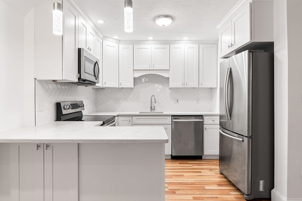 166 Quincy Shore Drive, Unit 108 Quincy, MA 02171 - Photo 2 of 36 a kitchen with stainless steel appliances granite countertop a refrigerator sink and stove