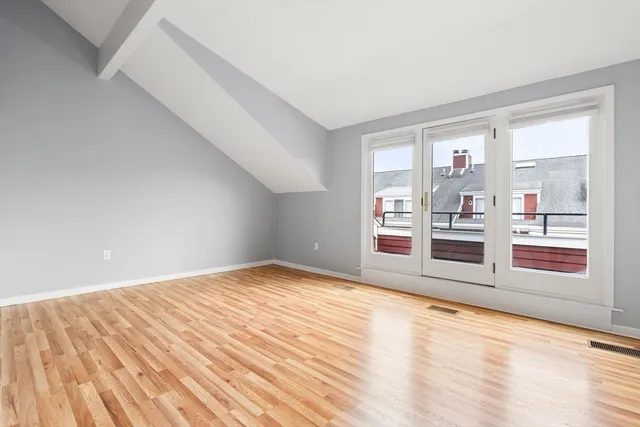 a view of an empty room with window and wooden floor