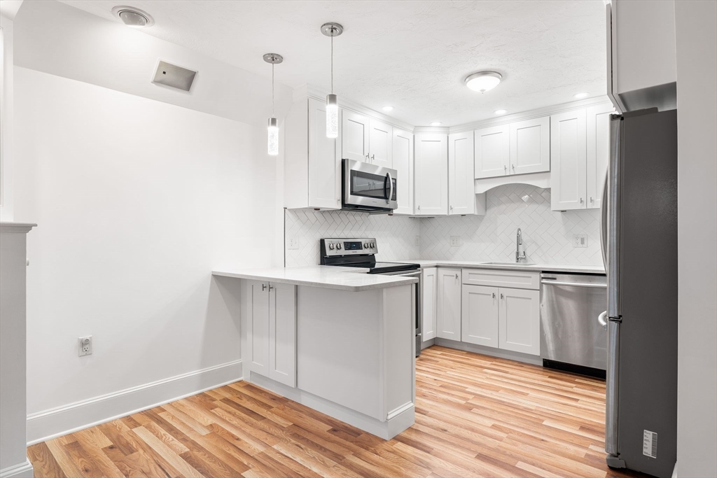 166 Quincy Shore Drive, Unit 108 Quincy, MA 02171 - Photo 4 of 36 a kitchen with stainless steel appliances granite countertop a sink a stove a refrigerator and white cabinets