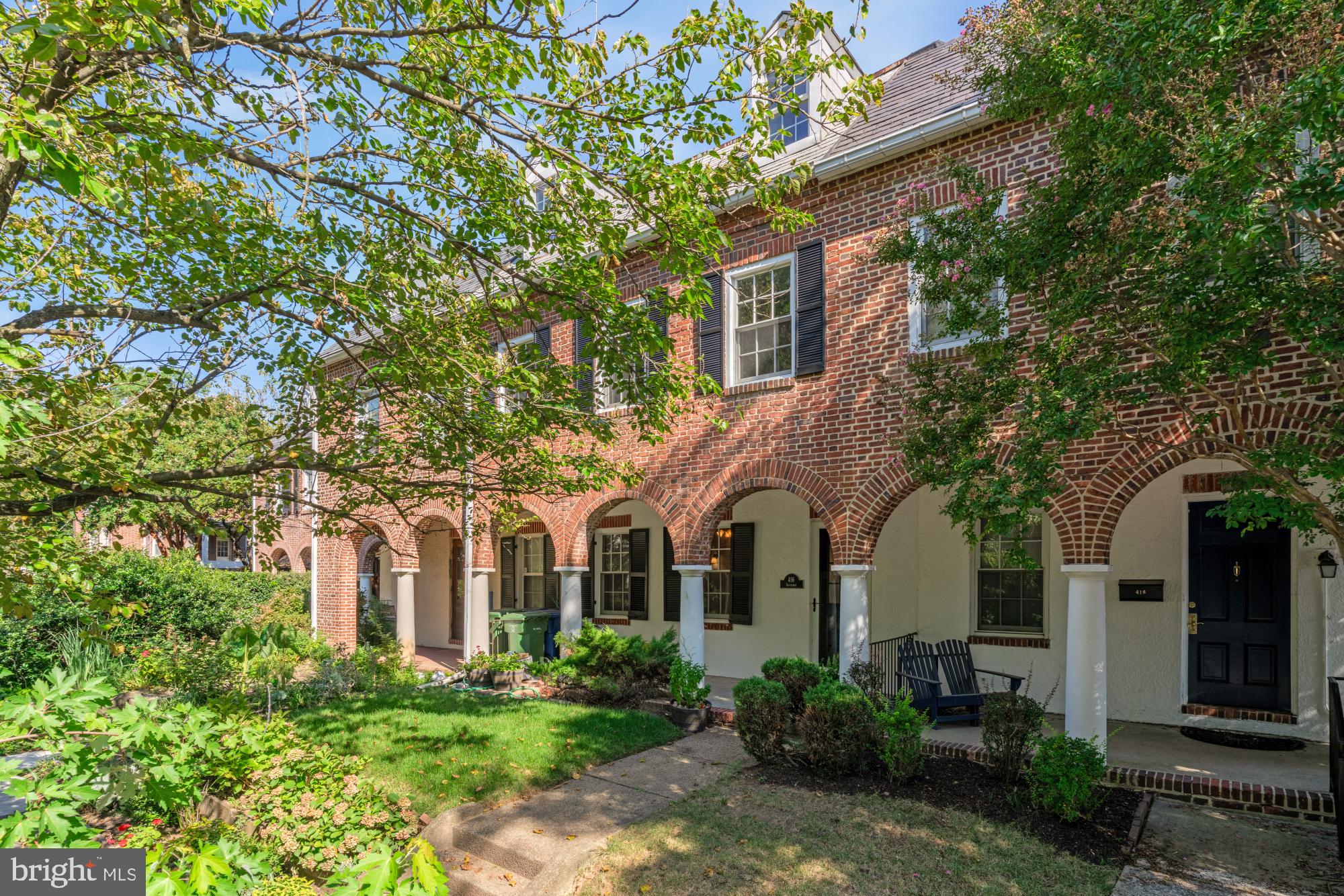 a view of a white house with large windows and a small yard