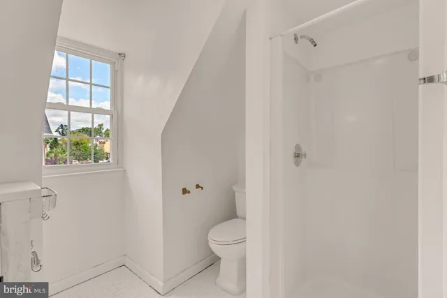 a bathroom with a granite countertop toilet a sink and a window