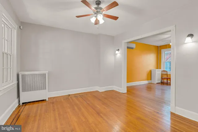a view of an empty room with window and wooden floor