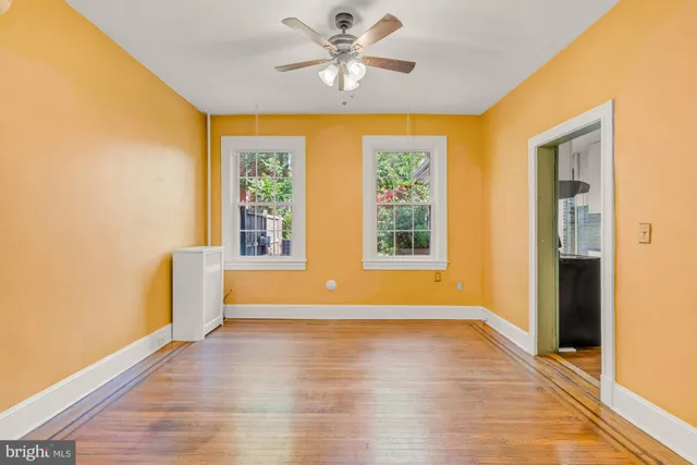 a view of an empty room with window and wooden floor