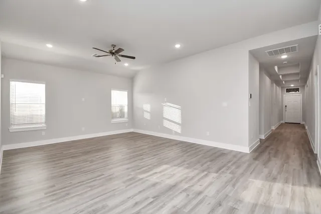 an empty room with wooden floor and windows