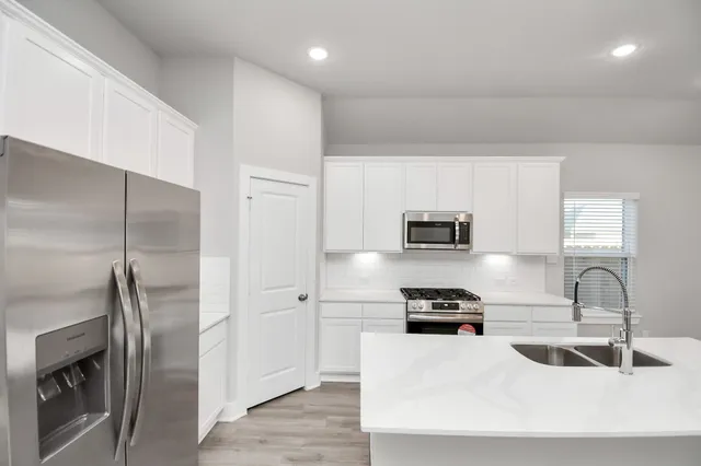 a kitchen with stainless steel appliances a refrigerator sink and white cabinets