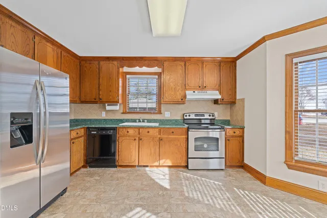 a large kitchen with stainless steel appliances granite countertop a stove a sink and a granite counter tops with a large window